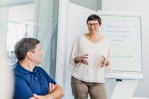 Female Business Consulting standing in front of a flip chart talking to workshop attendee